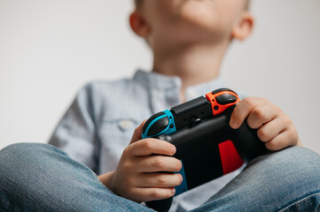 Happy boy playing video games holding game controller sitting on the coach in living room