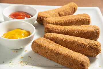 Vegan food, chickpea croquette and sauces on a white plate over wood, selective focus.