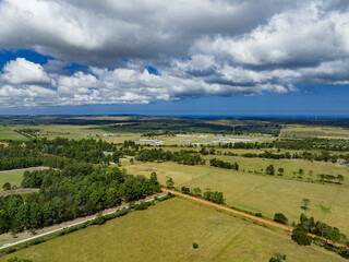 Fototapeta na wymiar Aerial view of lush fields with dramatic clouds hovering