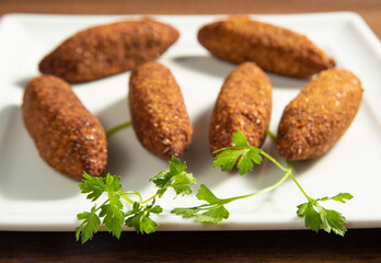 Vegan food, vegan kibbeh and sauce on a white plate, over wood, selective focus.