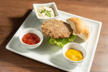 Vegan food, Vegan burger and sauces on a white plate, over wood, selective focus.