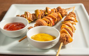 Vegan food, vegan skewers and sauces on a white plate, over wood, selective focus.