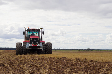 modern tractor in empty field with seasonal agriculture works