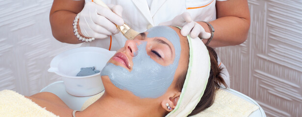 Young woman with facial mask lying in beauty health spa center and getting beauty skin treatment