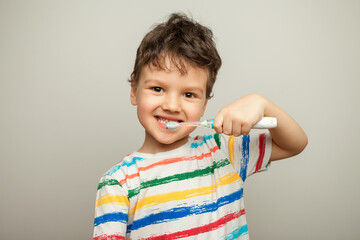 the child brushes his teeth. a boy with a toothbrush in his hands shows how to brush his teeth. - Powered by Adobe