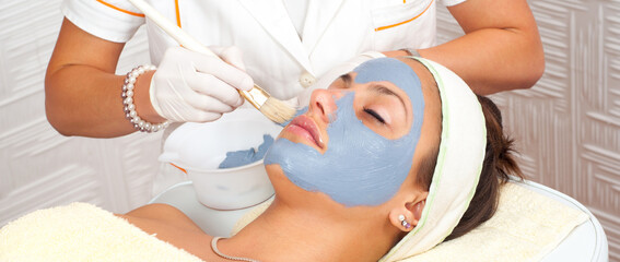 Young woman with facial mask lying in beauty health spa center and getting beauty skin treatment