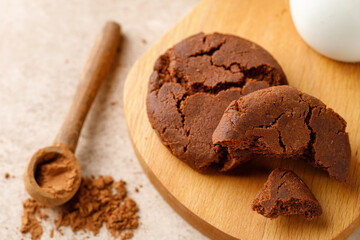 Cookies with cocoa for lunch with milk in bottle on a beige table. Wooden tray. Close up
