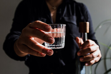 Bartender hands serving mexican mezcal shot in a traditional glass with tacos and food at background in Mexico	