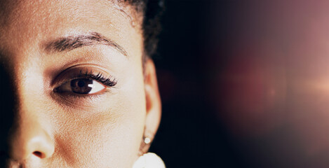 Lets make eye contact. Closeup shot of a beautiful young womans eye against a dark background.