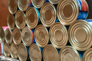 Many metal cans with canned food are stacked in rows. selective focus