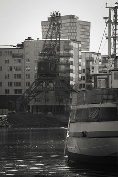 Part of a moored old ship with a harbor crane in the backdrop.