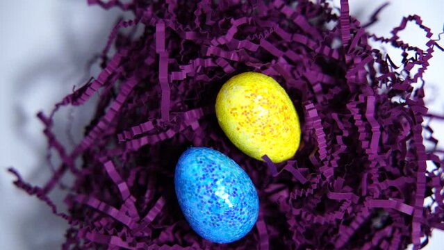 Happy Easter background. Colorful eggs in purple artificial bird's nest isolated on purple background. Easter concept.