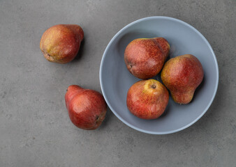 Red pears in a bowl over stone background