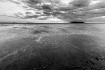 Shore of Trasimeno lake Umbria, Italy with moody clouds and island at the distance