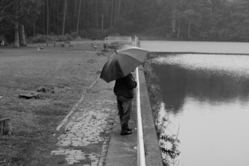 Lonely man reflecting and looking at the lake on a cloudy and rainy day