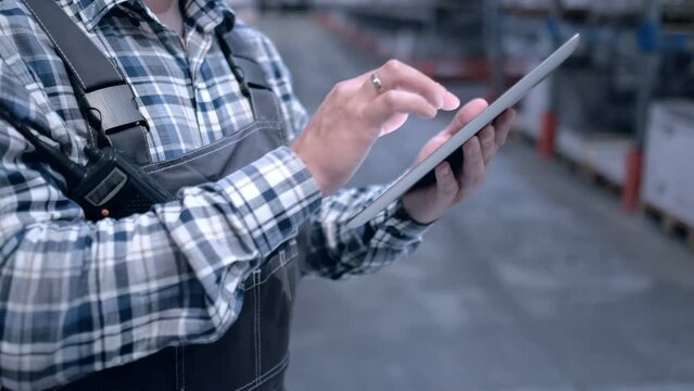 Worker male warehouse worker engineer man in a helmet working on the construction site of the warehouse, tablet computer, checking the warehouse, inspection of goods