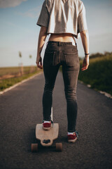 beautiful girl stands on a longboard one leg.poster, vertical banner, anonymous photography. faceless . Sunny day .