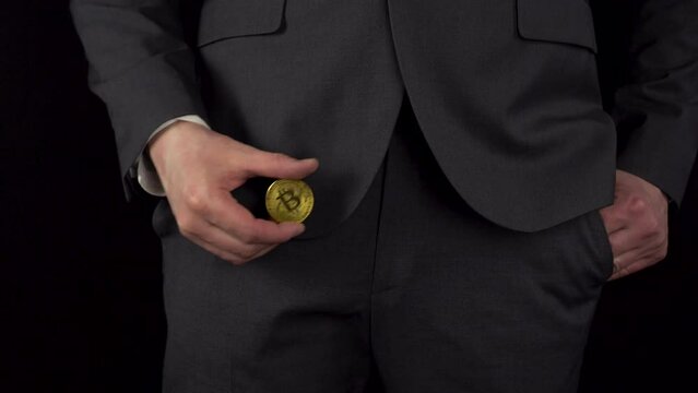 A young businessman in a suit takes out a bitcoin 