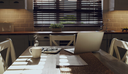 Ready for a day of working. Shot of a laptop and work supplies on a table in an empty kitchen during the day.