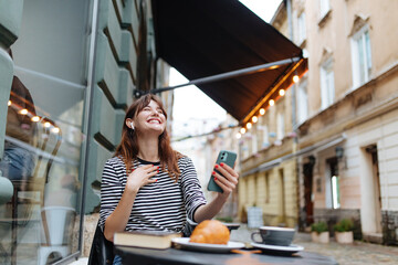 Obraz na płótnie Canvas Happy woman in earphones having video call on smartphone