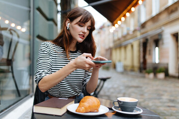 Positive woman using smartphone while resting at cafe