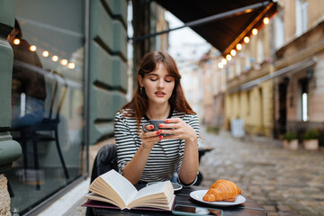 Woman spending leisure time with coffee and book at cafe