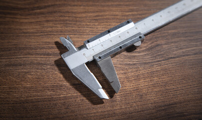 Vernier caliper on the wooden background.