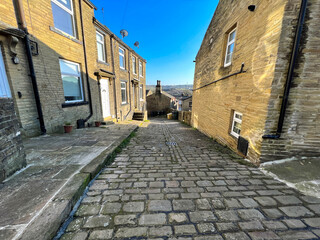 Looking down, Back Field, with old stone cobbles, cottages, and distant hills in, Thornton, Bradford, UK