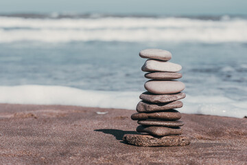 Zen pebbles in the sand with the sea in the background, symbol of peace and balance.stone stack