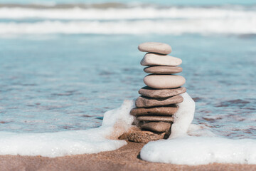 Zen pebbles in the sand with the sea in the background, symbol of peace and balance.stone stack