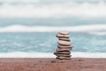 Fototapeta na wymiar Zen pebbles in the sand with the sea in the background, symbol of peace and balance.stone stack