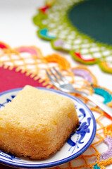 Traditional Colombian dessert, called Enyucado, made of cassava as a base ingredient and pieces of coconut and grated cheese,soft and crunchy texture, cooked in the oven. Background colorful. Closeup.