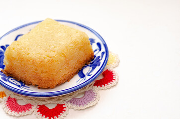 Traditional Colombian dessert, called Enyucado, made of cassava as a base ingredient and pieces of coconut and grated cheese,soft and crunchy texture, cooked in the oven.Background white. Closeup.