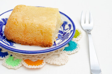 Traditional Colombian dessert, called Enyucado, made of cassava as a base ingredient and pieces of coconut and grated cheese,soft and crunchy texture, cooked in the oven.Background white. Closeup.