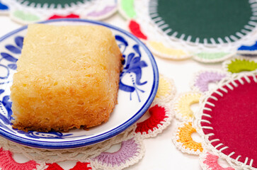 Traditional Colombian dessert, called Enyucado, made of cassava as a base ingredient and pieces of coconut and grated cheese,soft and crunchy texture, cooked in the oven.Background colorful. Closeup.