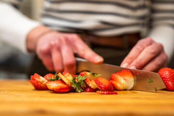 Woman in the kitchen cutting strawberries on a wooden cutting board