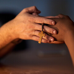 Finding comfort in religion. Closeup shot of a two people holding hands in support with a rosary.