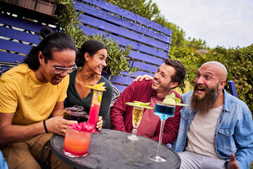 Happy friends celebrating drinking cocktails. Group of smiling young people having fun terrace bar