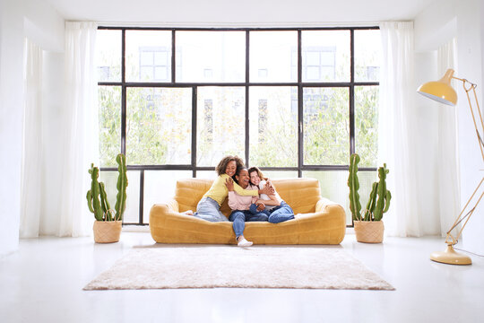 Three young multiracial only women hugging sitting at sofa living room. Happy lady Mixed race smiling friends together at home.