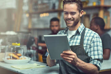 Fototapeta premium Social media is great for boosting small business visibility. Shot of a young man using a digital tablet in the store that he works at.