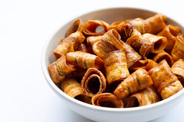 Dried banana rolled chips on white.