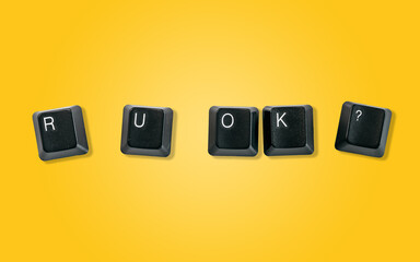 Computer keyboard keys spelling R U OK?, isolated on a yellow background