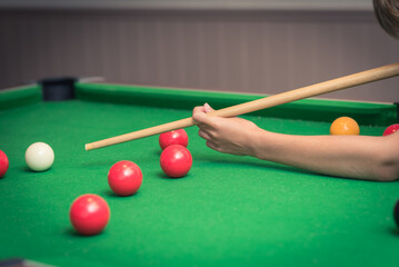 A  boy  plays billiard or pool in club. Young Kid learns to play snooker. Boy with billiard cue...
