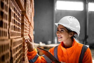 Female factory worker checking quality of the products before shipment in brick factory.