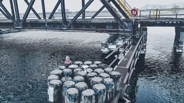 Snow falls in early dawn at the old historic swing bridge with the walkway extending out