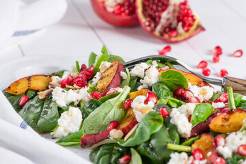 Salad. Spring vegetable salad. Fresh vegetable salad with grilled peach, pomegranate, spinach and fresh cheese.