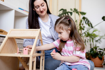 Montessori material. Home education. Mom and daughter are learning dollhouse furniture.