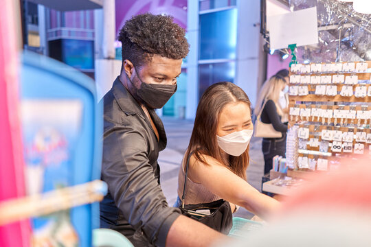 Two multethnic friends wearing mask buying jewellery inside a mall