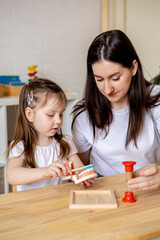 Montessori material. Mom teaches her daughter how to brush her teeth while playing.