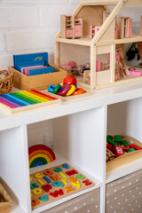 Montessori material. White shelves in a room with neatly arranged toys.